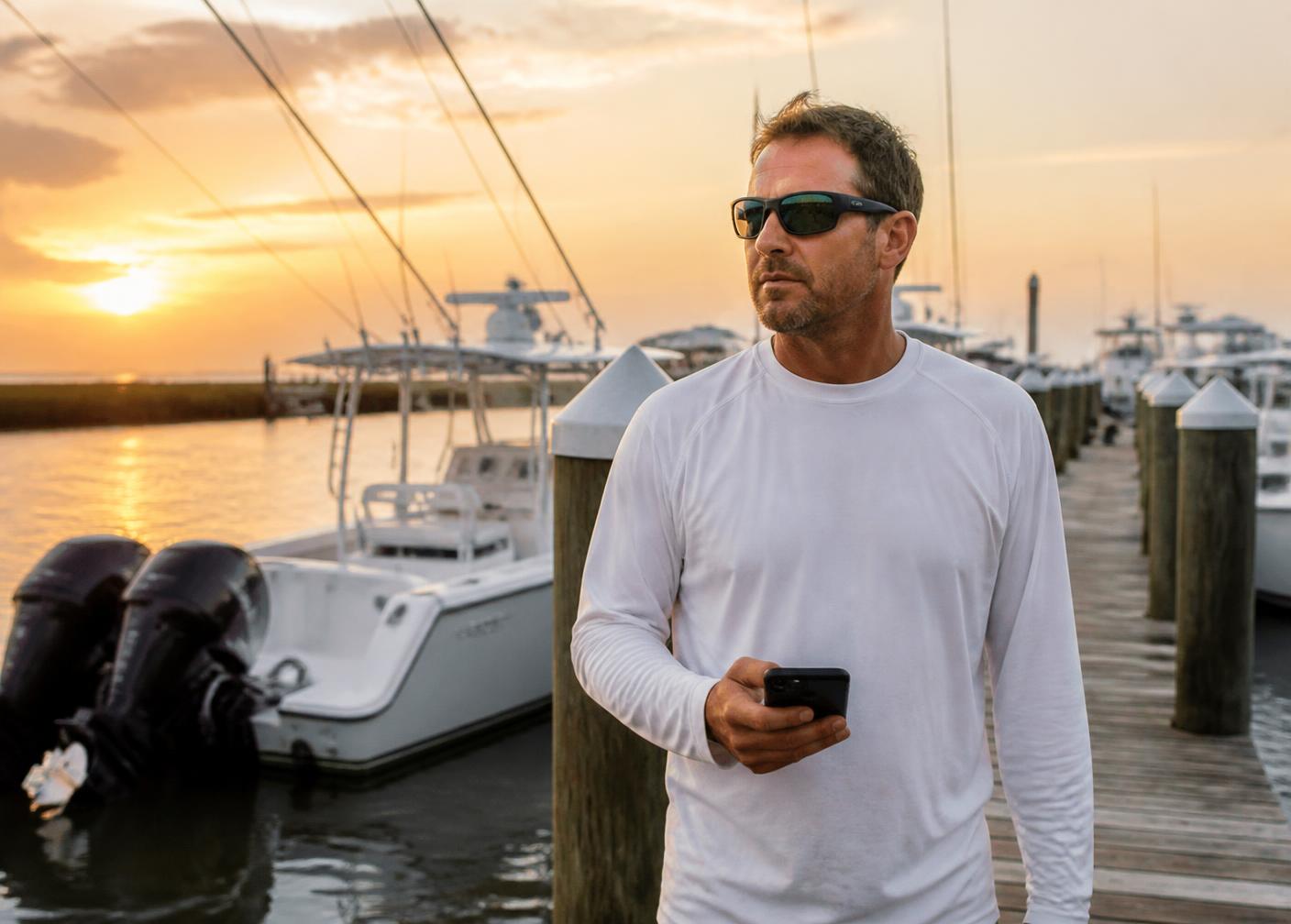 Charter captain checking his bookings on a phone at a Gulf Coast marina at sunrise