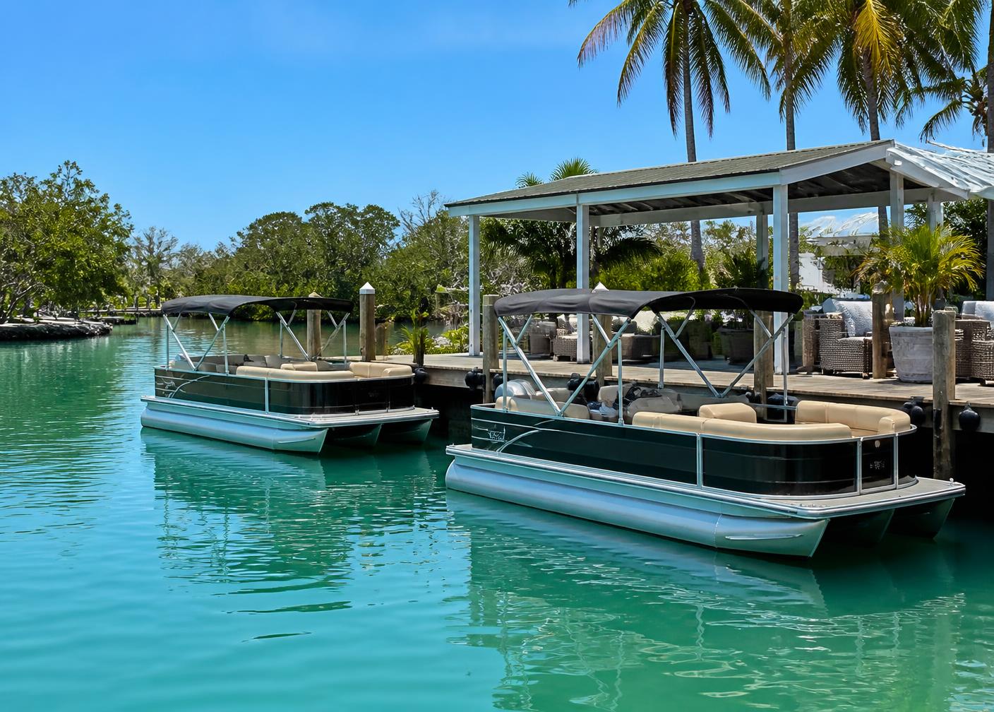Two pontoon rental boats tied to a dock on calm emerald coastal water